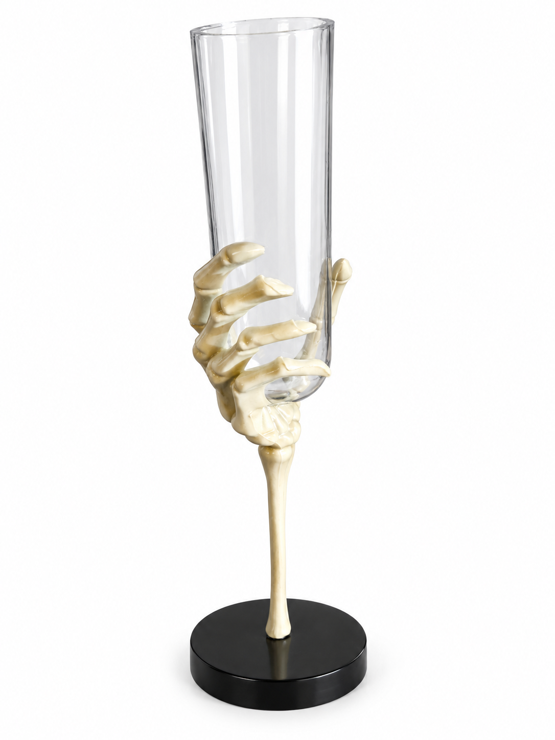 Vase cylindrique transparent maintenu par une main de squelette sur un socle noir et un fond blanc